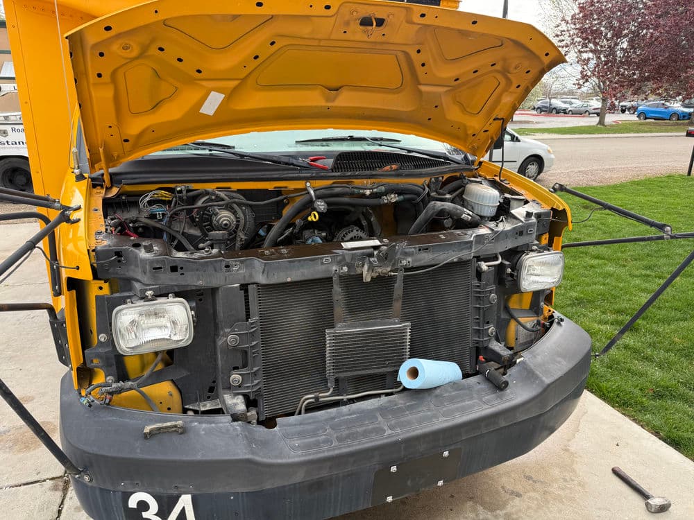 Yellow school bus with open hood, showcasing engine components and maintenance details.