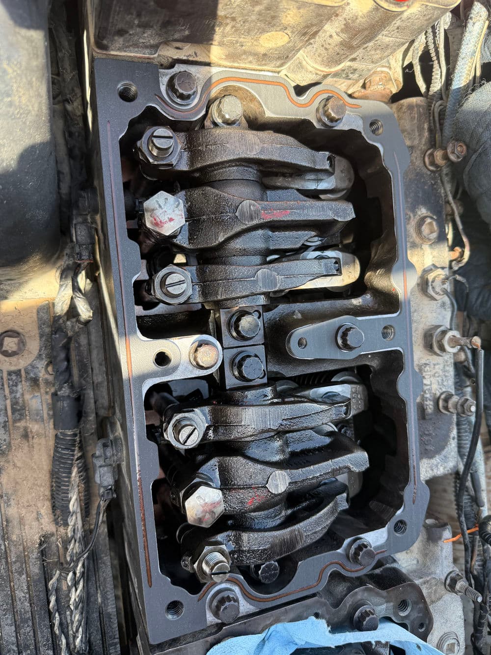 Engine valve train assembly with rocker arms and bolts, showcasing automotive mechanics.