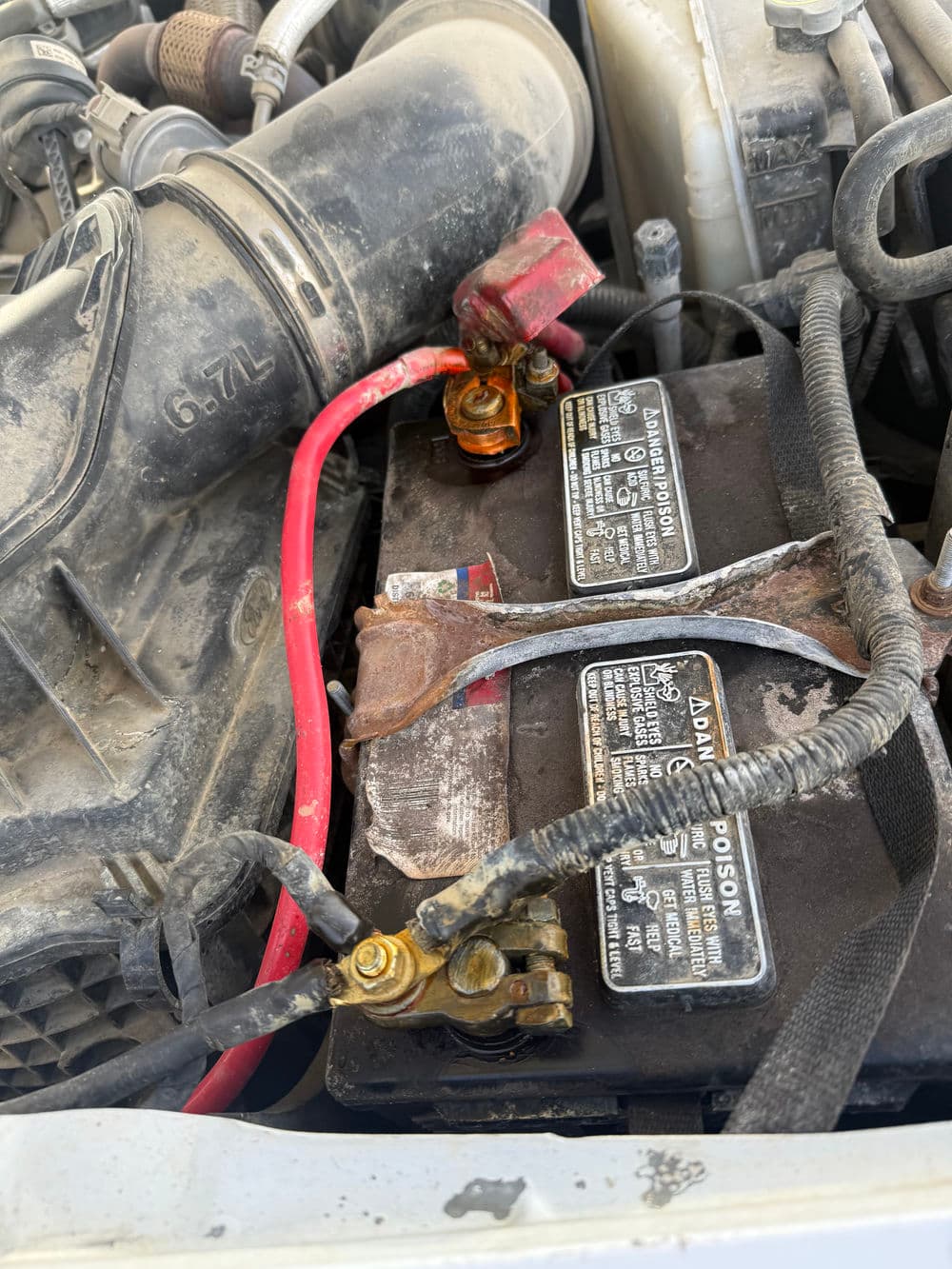 Car battery connections showing corrosion and worn cables under the hood.
