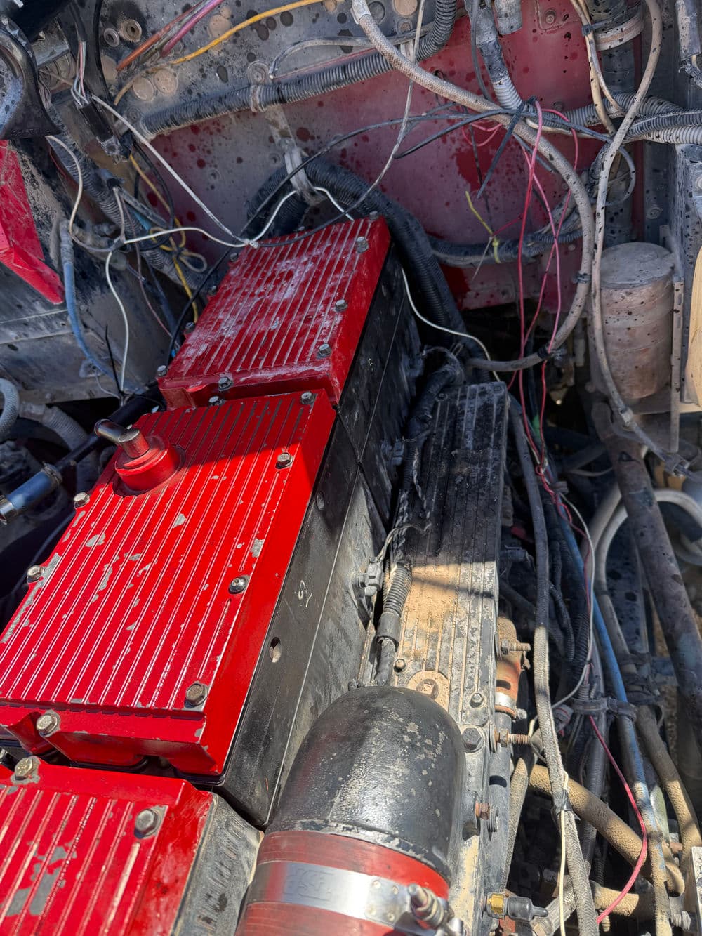 Close-up of a red and black engine with exposed wiring and components in a vehicle.