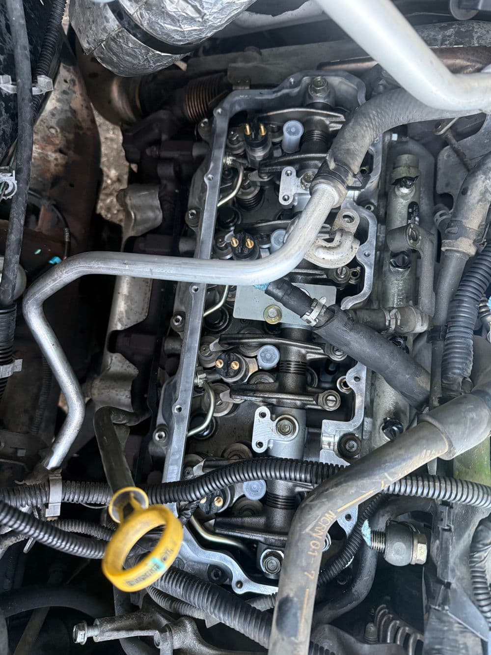 Close-up of an automotive engine's valve cover and components for maintenance and repair.