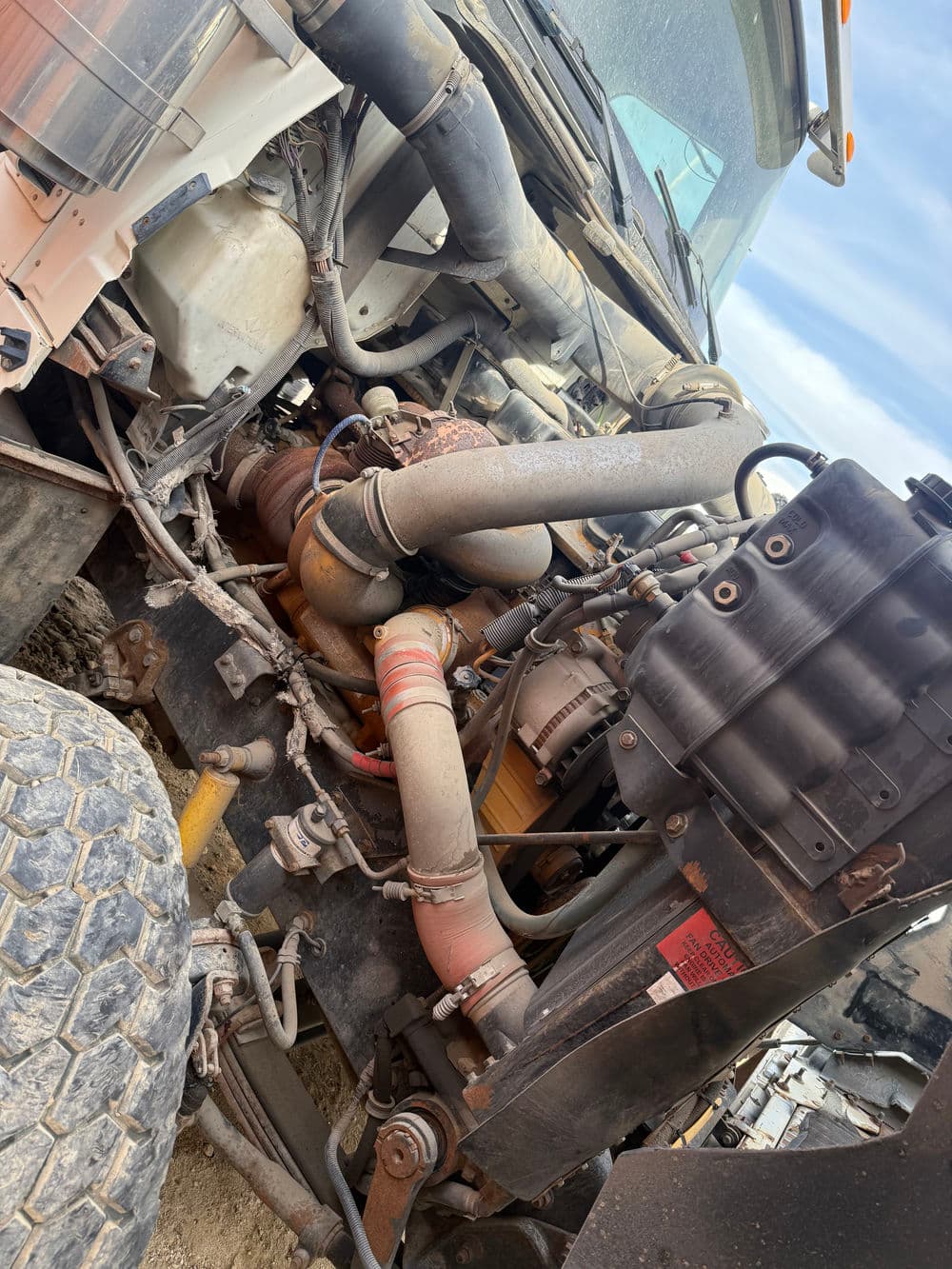 Close-up of heavy machinery engine components, showcasing intricate tubing and mechanical parts.