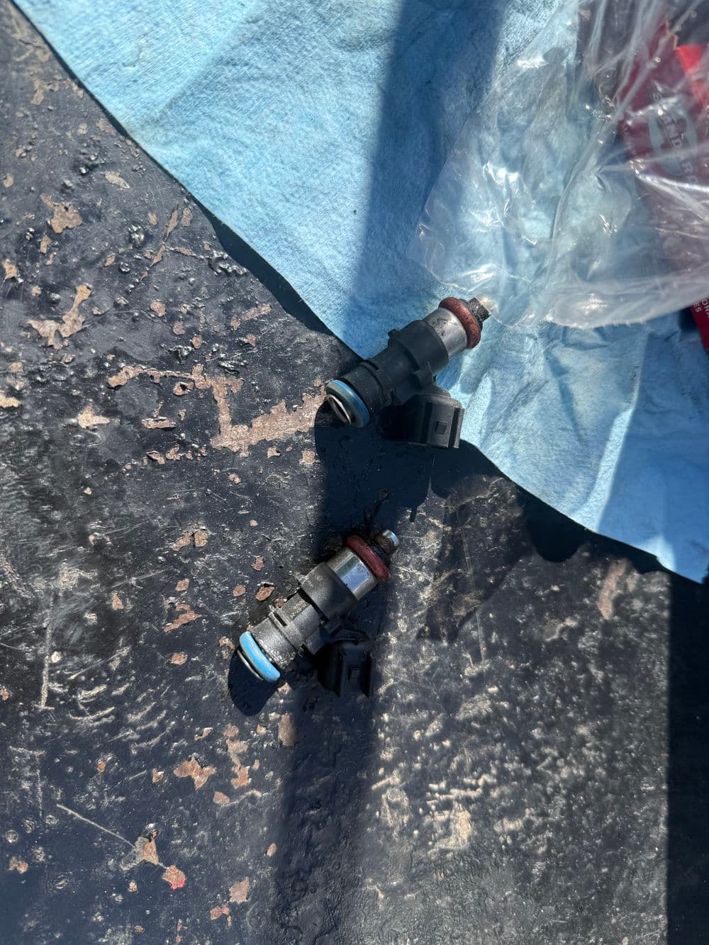 Fuel injectors on a blue towel, background showing a textured surface.