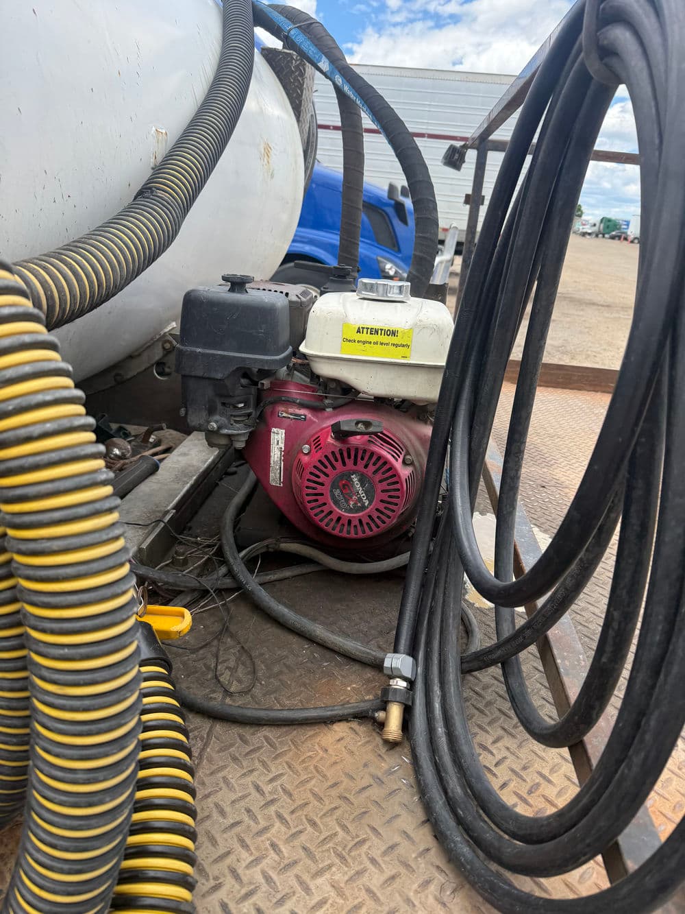 Small gas engine mounted on equipment with hoses in an outdoor setting.