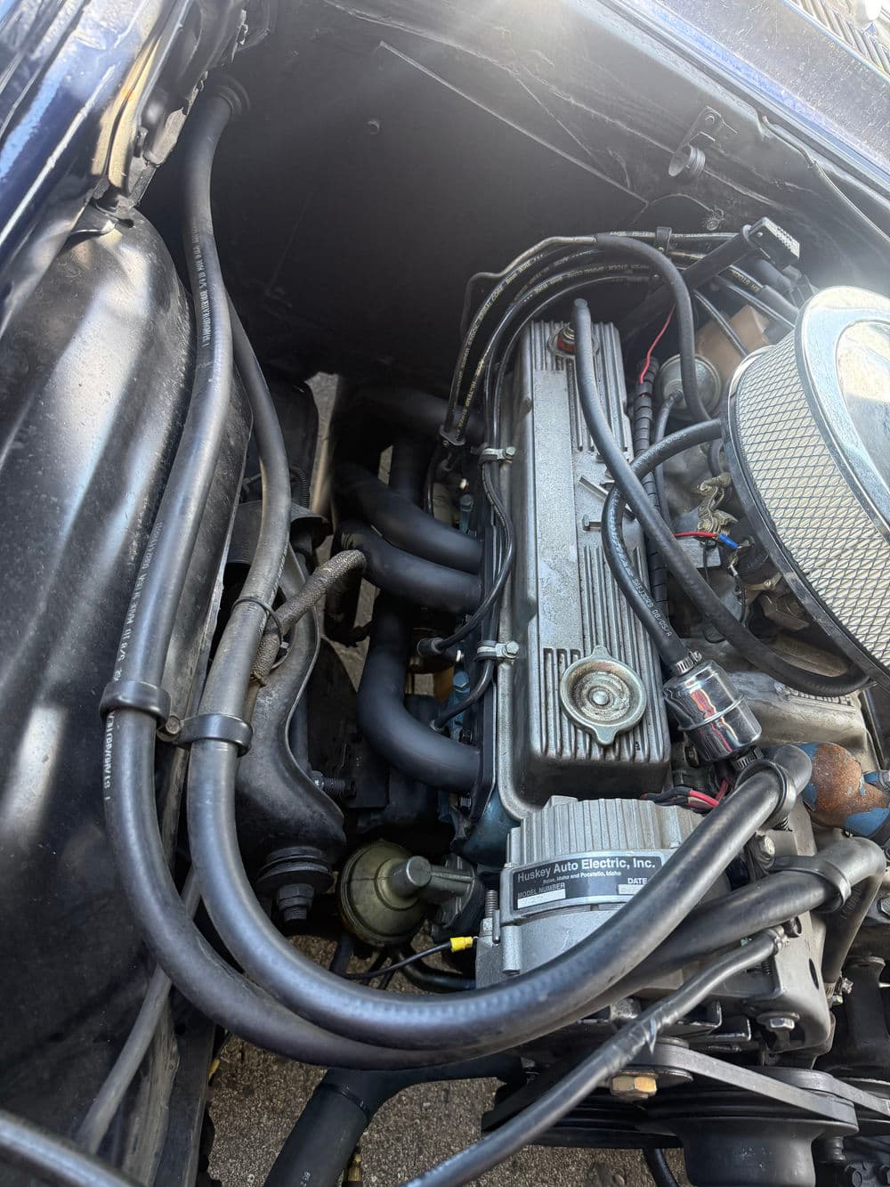 Engine compartment with wires and tubing of a classic car, showcasing detailed components.
