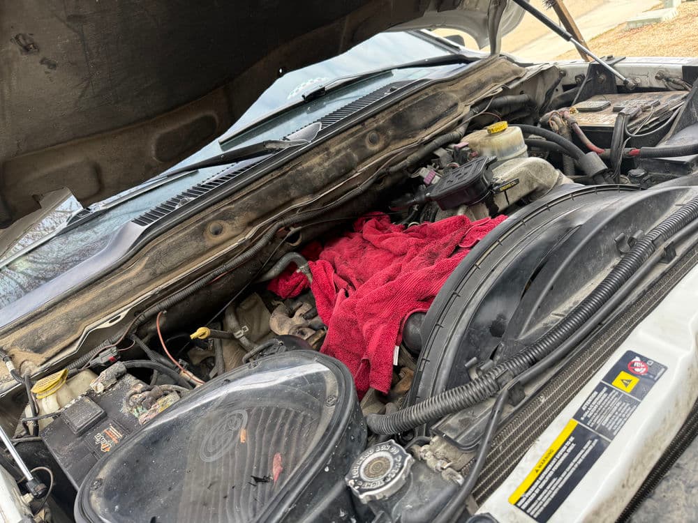 Engine bay with a red towel resting on components and visible mechanical parts.