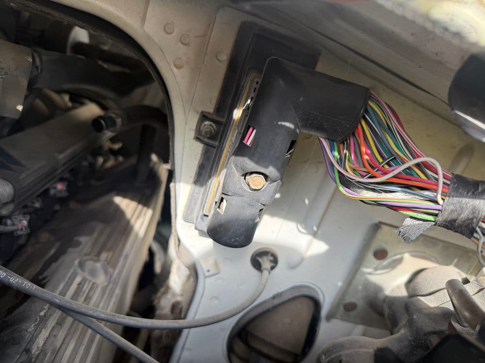 Close-up of engine wiring harness connected to vehicle's electronic control module.