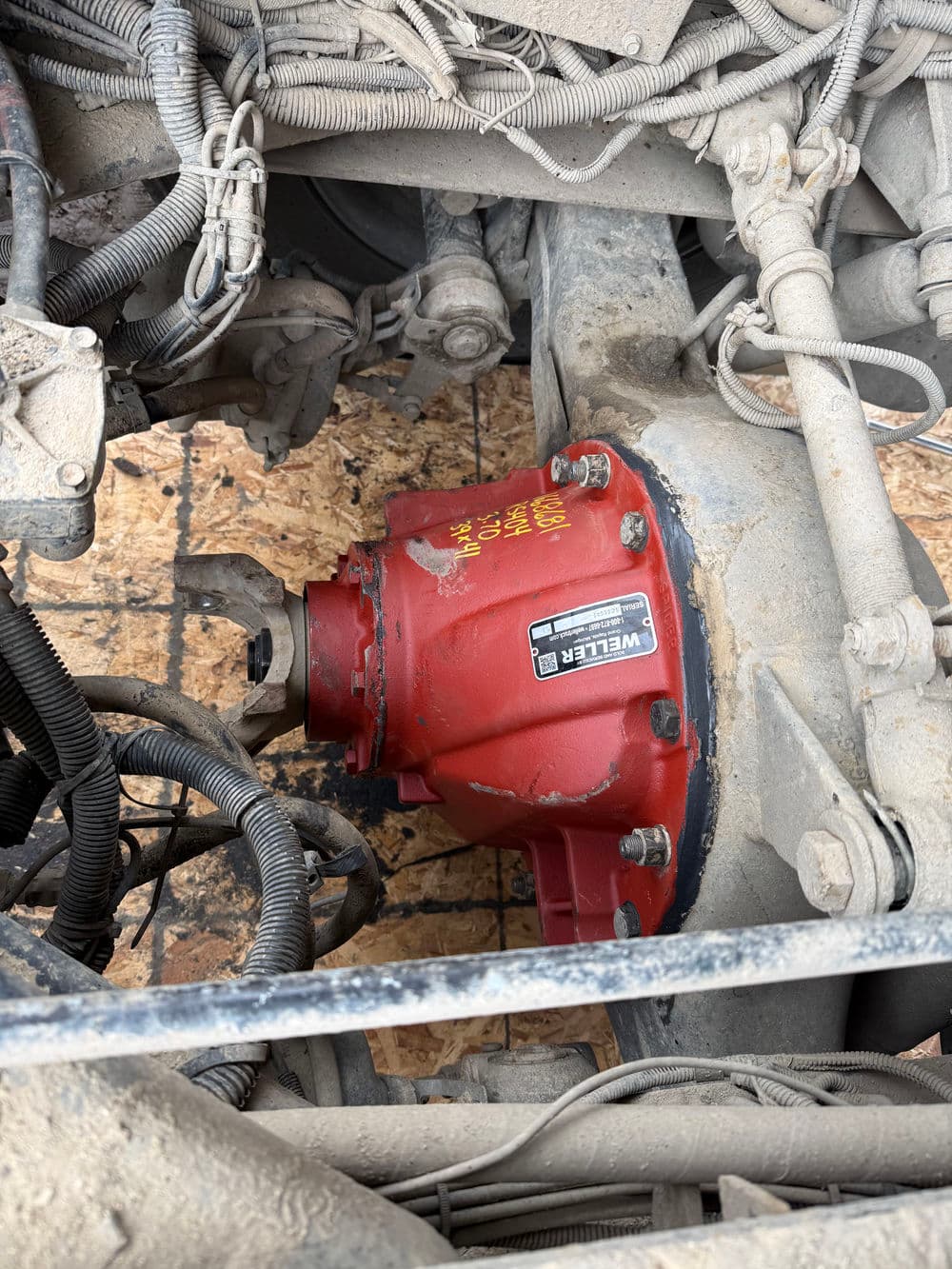 Red differential under a vehicle, showcasing mechanical components and wiring.