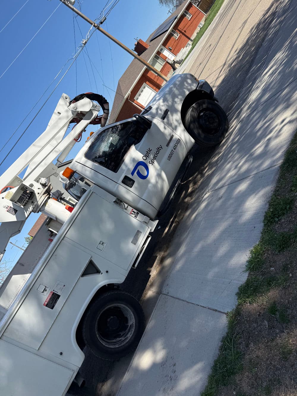 Utility truck with aerial lift on residential street for maintenance work.