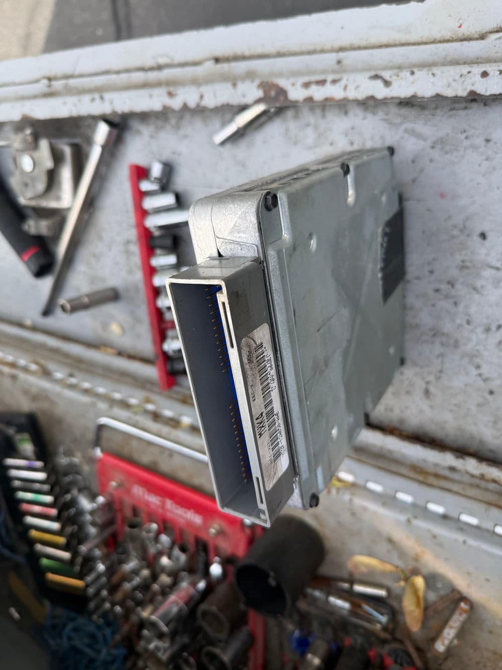 Automotive ECU on workbench with tools, showcasing electronic control unit details.