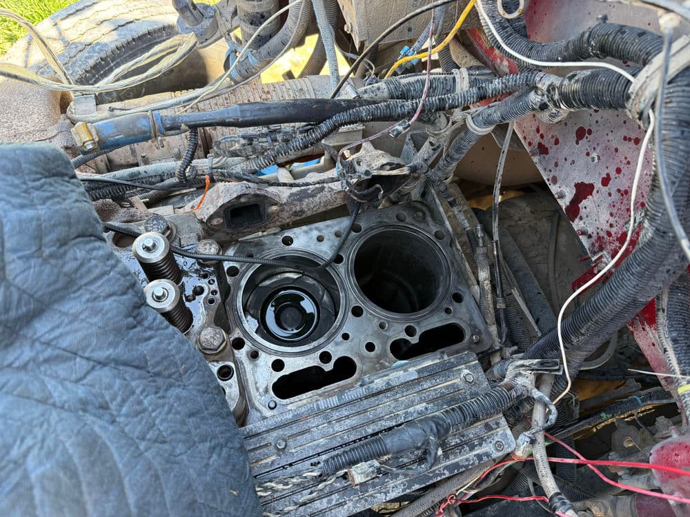 Engine block with exposed cylinders and wiring, showing wear and mechanical details.